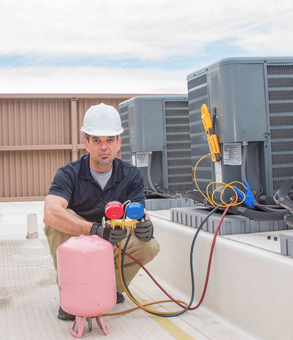 NATE-certified HVAC technician servicing AC unit on rooftop